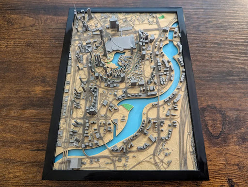 3D model of a city layout with roads and waterways on a wooden surface