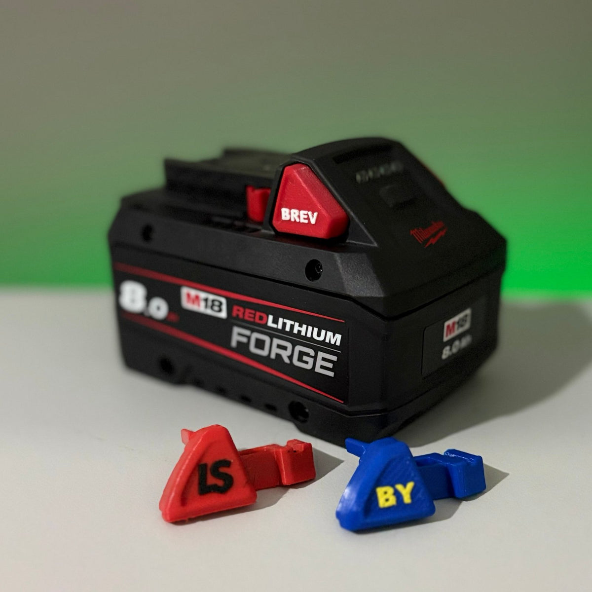 Z Battery Buttons personalised red and blue battery release buttons, shown beside a Milwaukee M18 battery